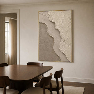 Neutral textured wall art in a warm dining room with a gold frame.