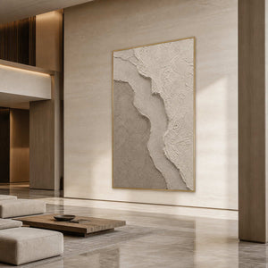 Large neutral textured wall art in a modern hotel lobby with a gold frame.