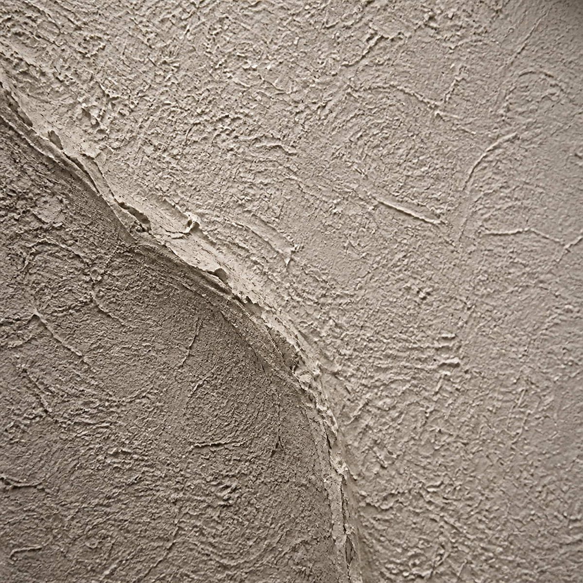 Close-up of rough sand, taupe, and ivory sculpted surface texture.