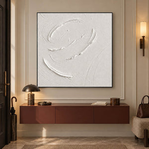 White minimalist relief painting with raised circular gestures in a black frame in an entryway.