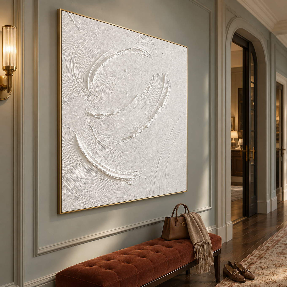 White minimalist relief painting with raised circular gestures in a gold frame in a hallway.