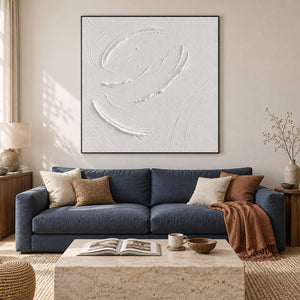 White minimalist relief painting with raised circular gestures in a black frame in a living room.