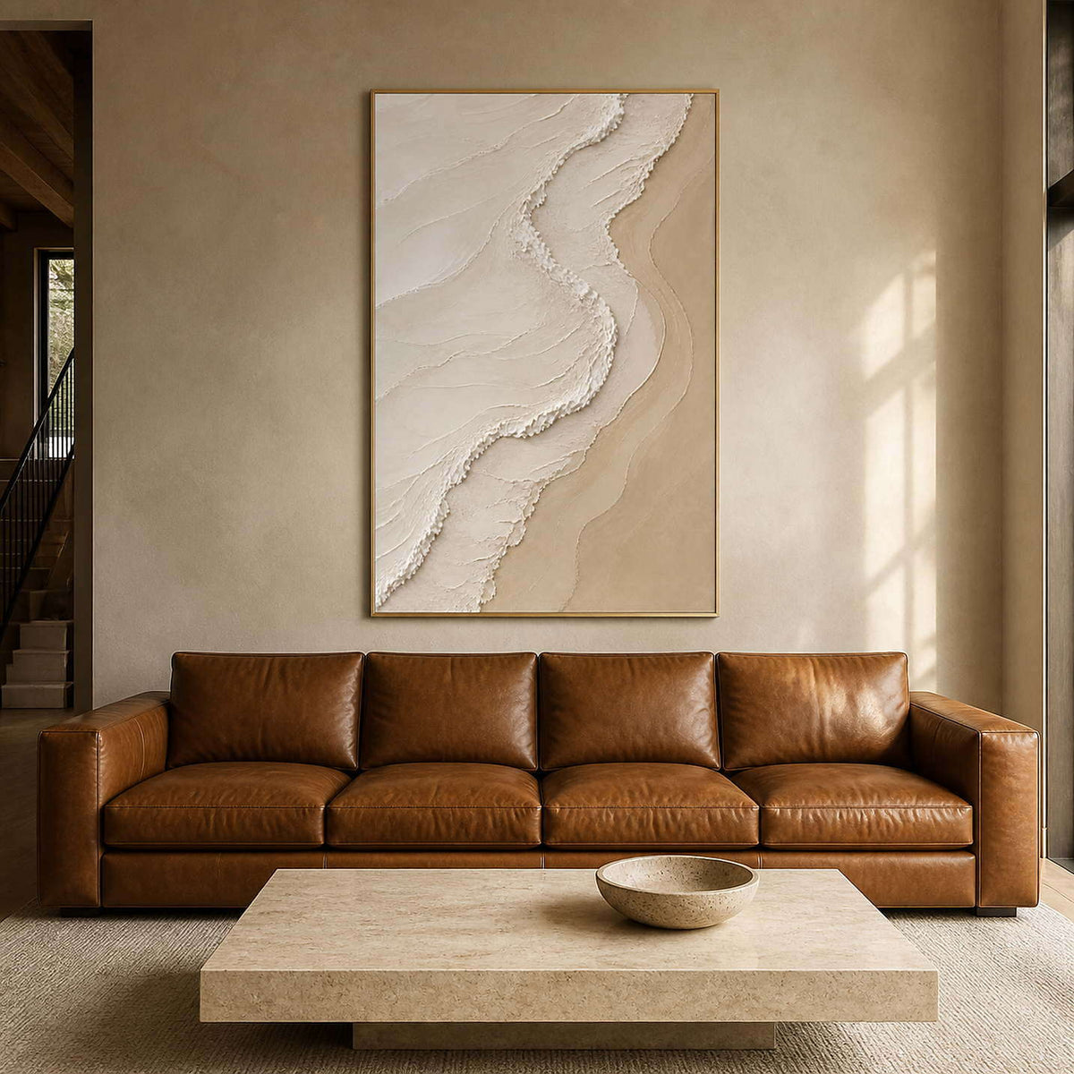 Textured neutral wall art above a caramel leather sofa in a warm living room.