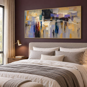 Hand-painted textured abstract wall art in golden ochre, smoky violet, slate blue, and charcoal, displayed in a bedroom in a gold frame.