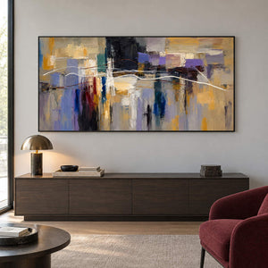 Hand-painted textured abstract wall art in golden ochre, smoky violet, slate blue, and charcoal, displayed in a lounge in a black frame.