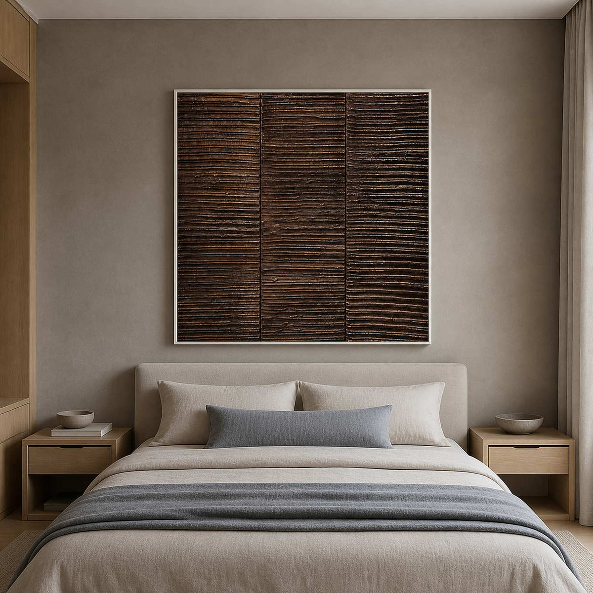 White framed brown textured painting above a bed with pale gray bedding.