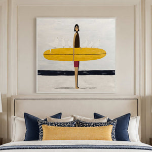White framed surfer artwork above a bed with navy and yellow accent pillows.
