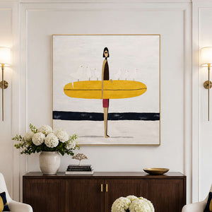 Gold framed surfer artwork above a hotel lobby cabinet between brass wall lamps.