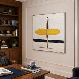 Silver framed surfer artwork above a wooden desk beside dark study shelves.