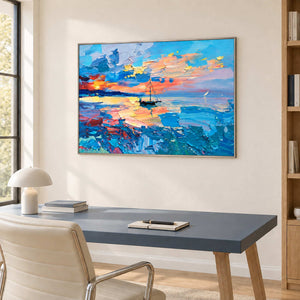 Sunset sea painting above a blue desk beside a window.
