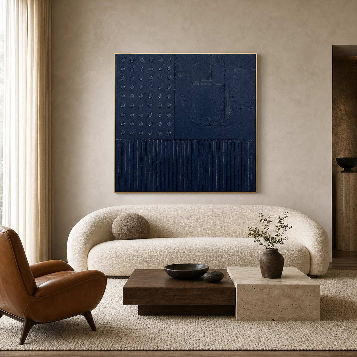 Navy blue geometric relief artwork above a warm contemporary living room sofa.