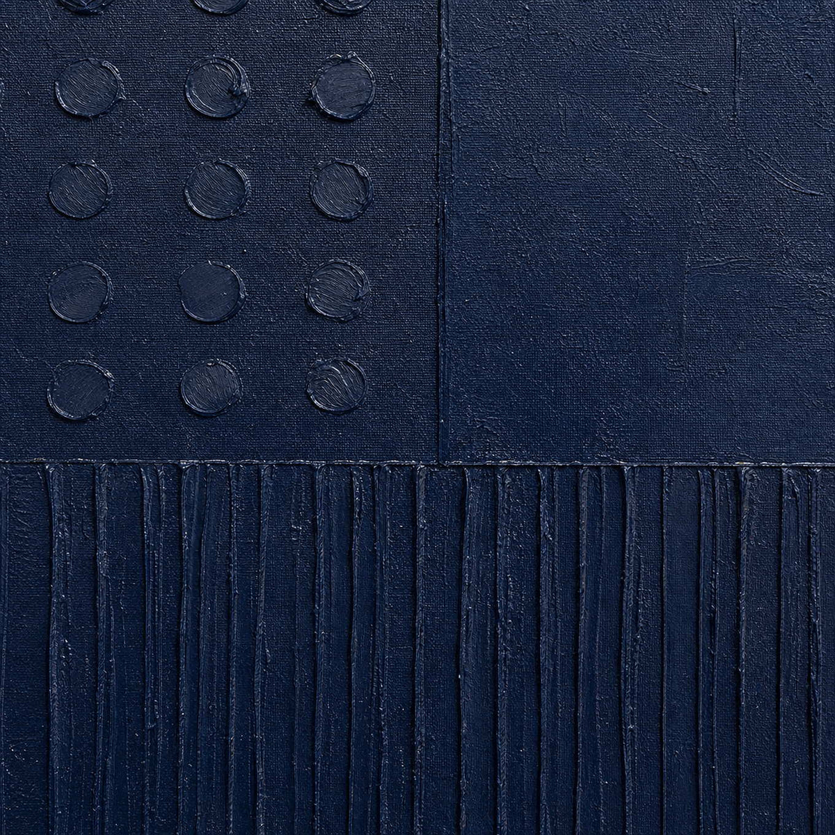 Close-up of navy painted canvas, raised dots, and carved lines.