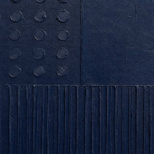 Close-up of navy painted canvas, raised dots, and carved lines.