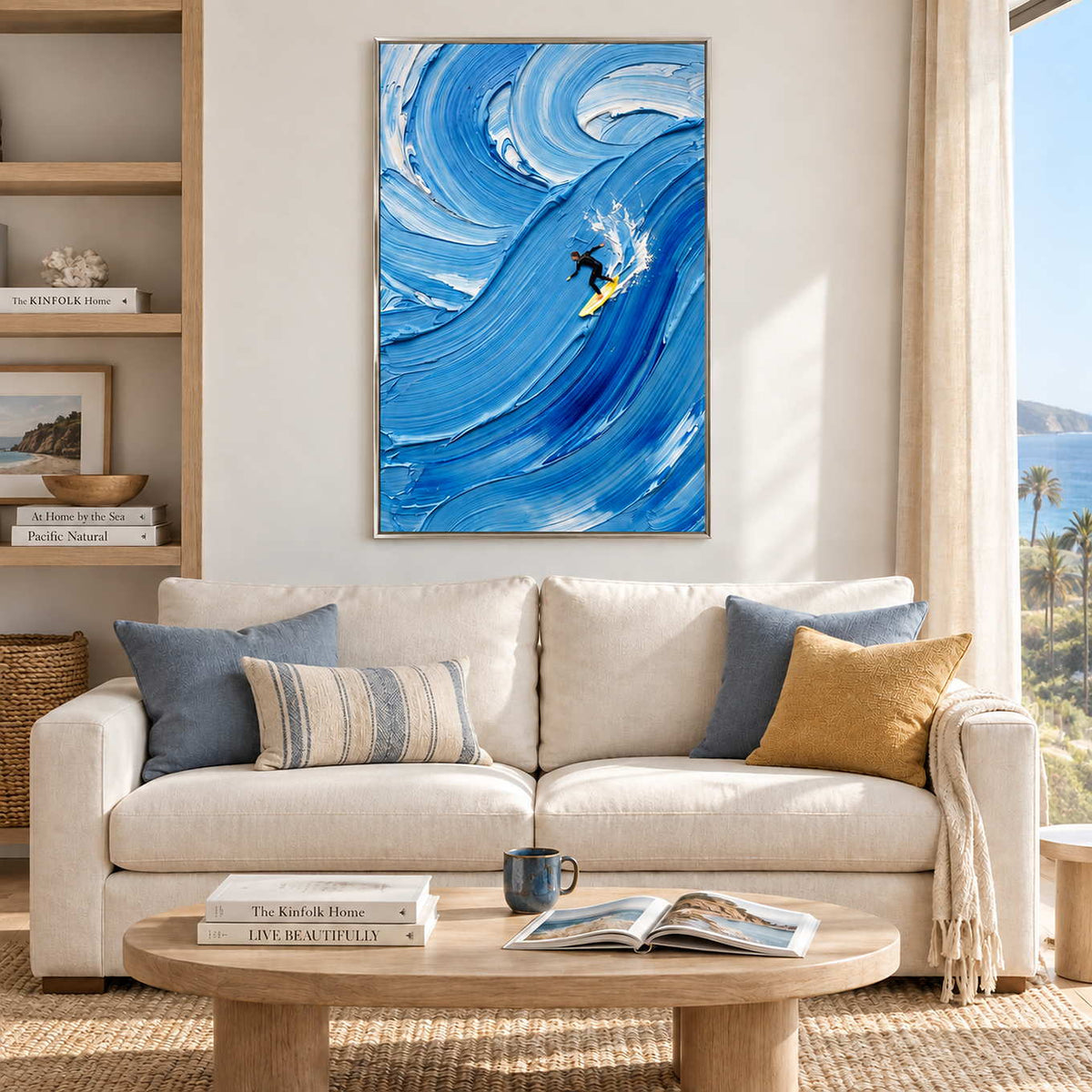 Riding the Wave in a silver frame above a cream sofa with blue and mustard cushions beside a bright window.