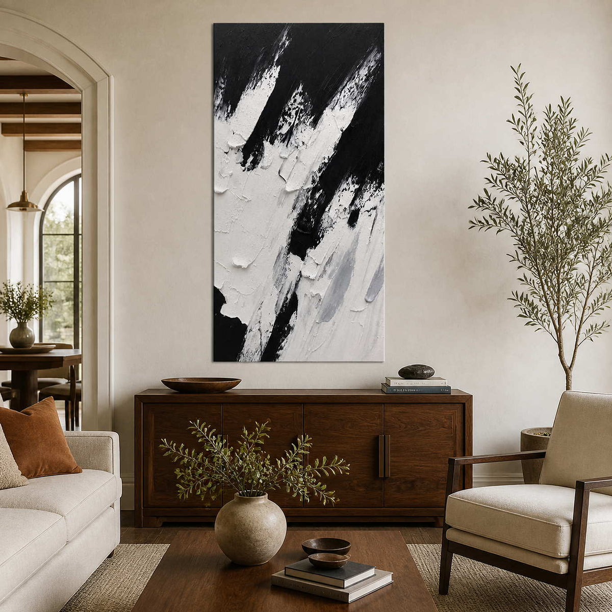 Rising into the Wind, a tall black and white textured abstract painting above a walnut sideboard in a warm living room.
