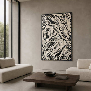 Black framed abstract painting with curved bands beside seating in a design studio lounge.