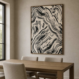 Wood framed abstract artwork with flowing black bands beside a wooden dining table.