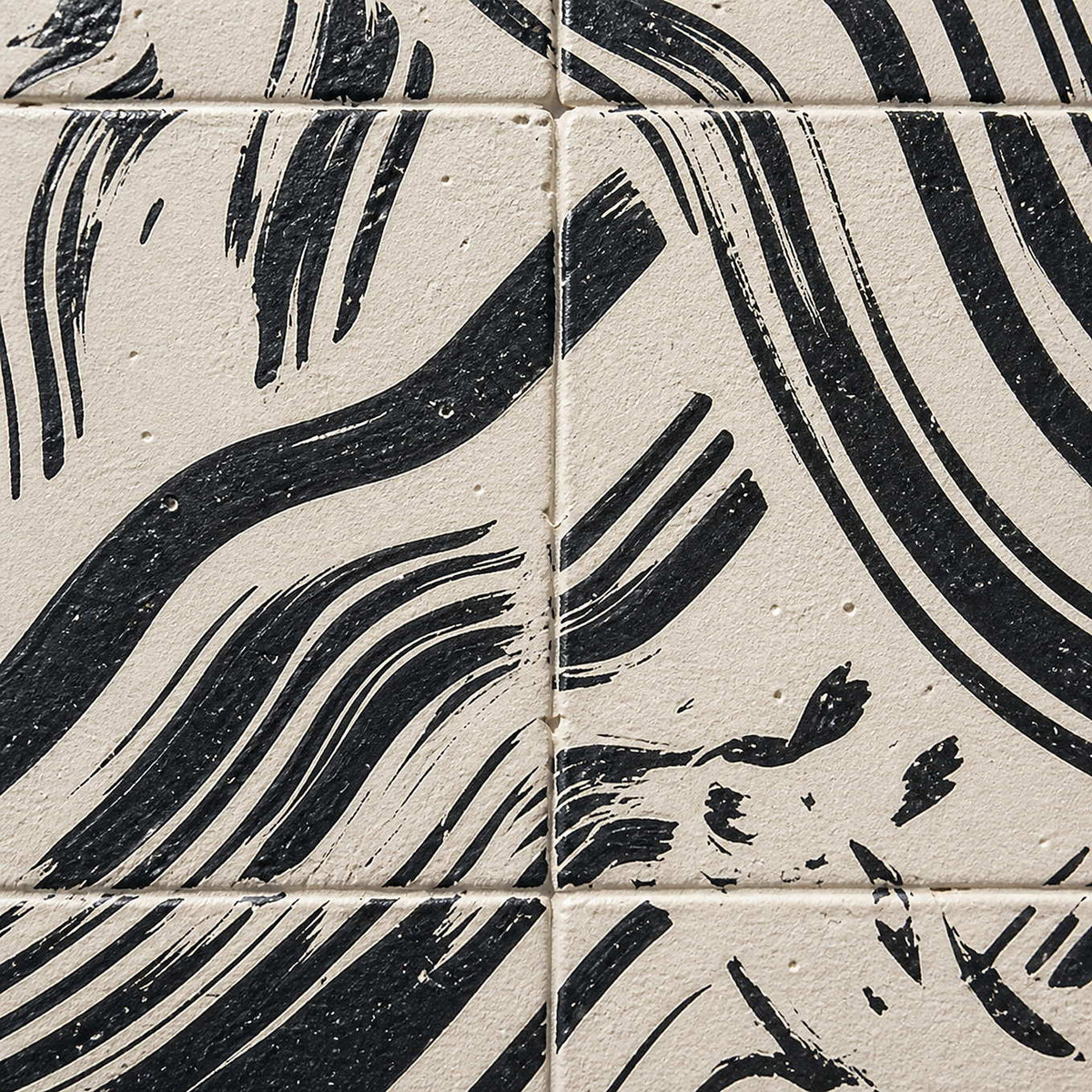 Close-up of black curved marks and recessed grid divisions across a pale textured surface.