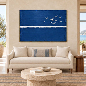 Room to Fly in a gold frame above a cream loveseat and round pale stone table in a bright commercial lobby.