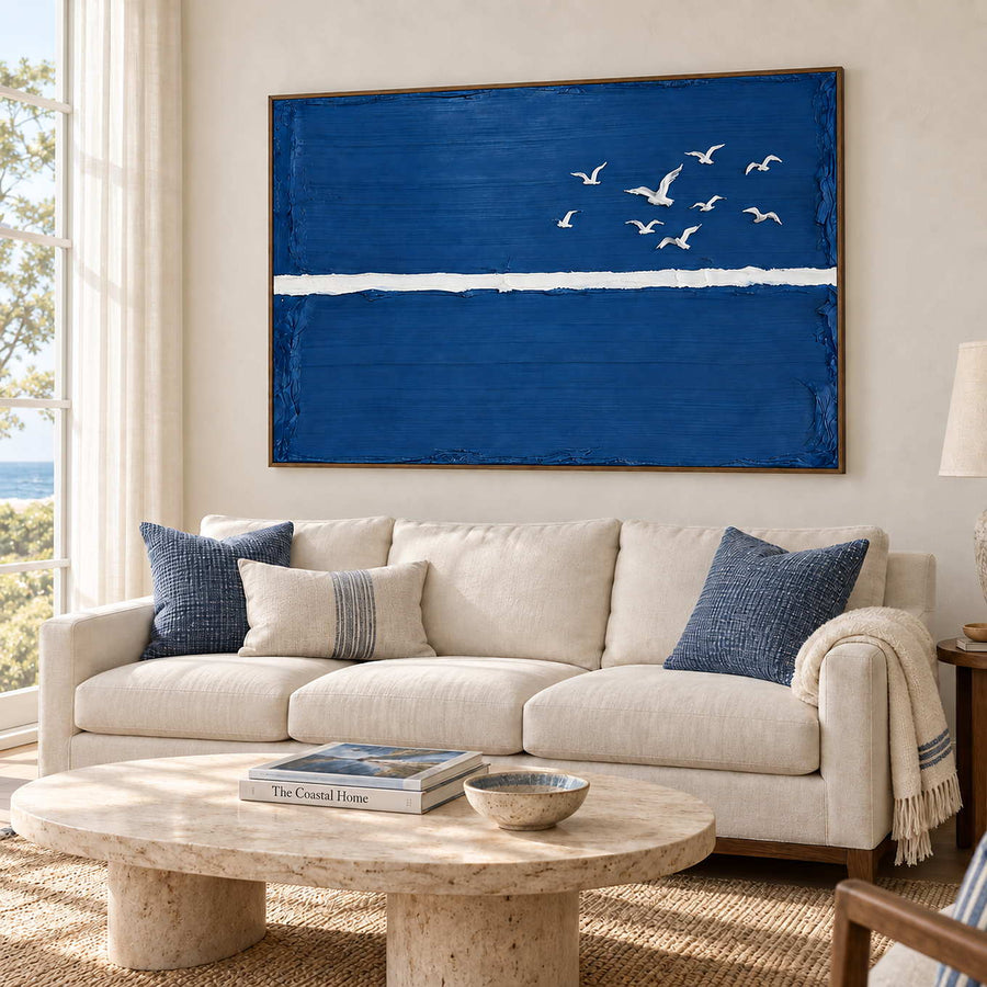 Room to Fly in a wood frame above a cream sofa with blue cushions and a pale oval stone coffee table.