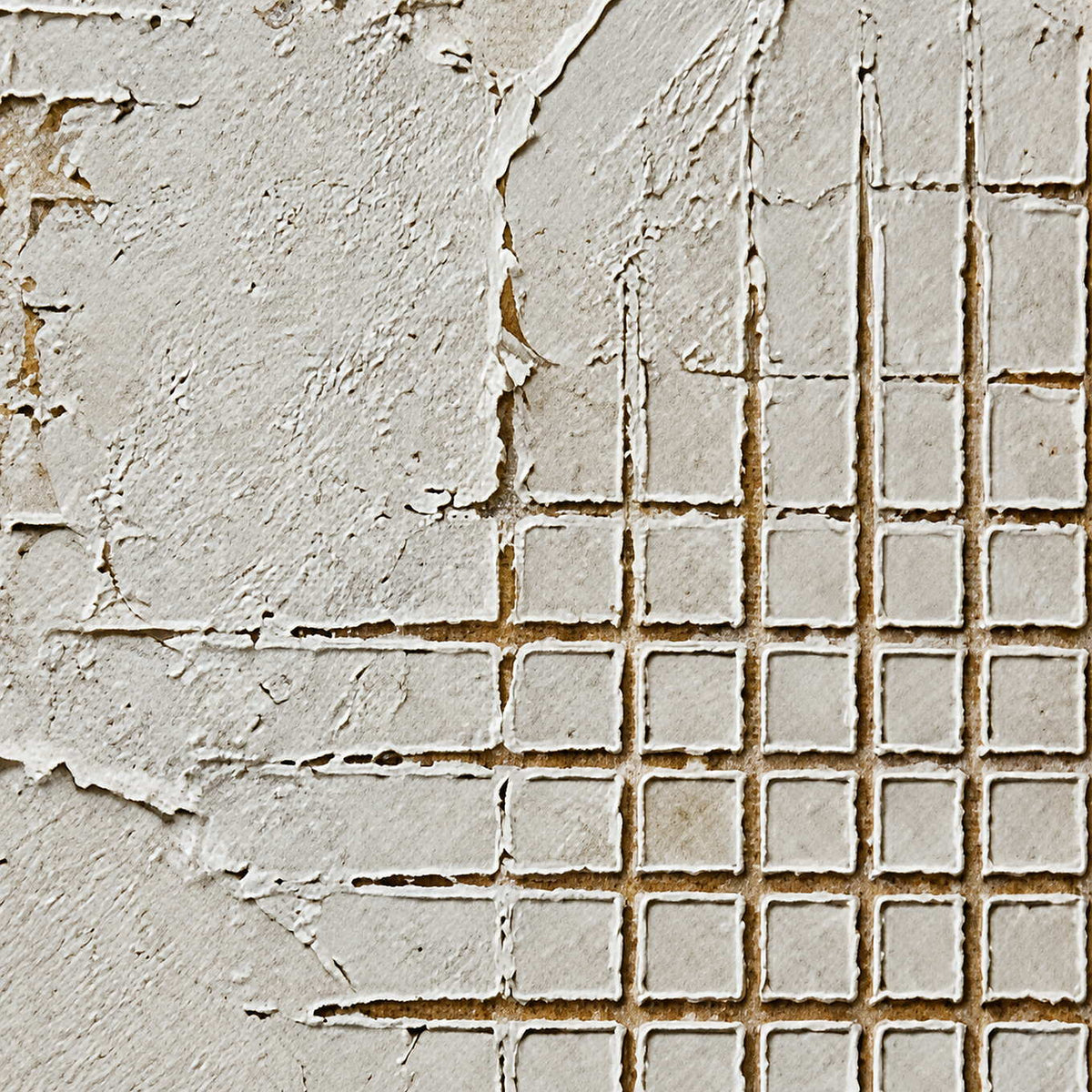 Close-up of broken white plaster and precisely incised grid texture.
