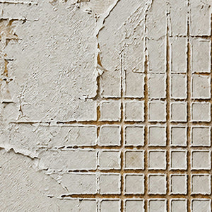 Close-up of broken white plaster and precisely incised grid texture.