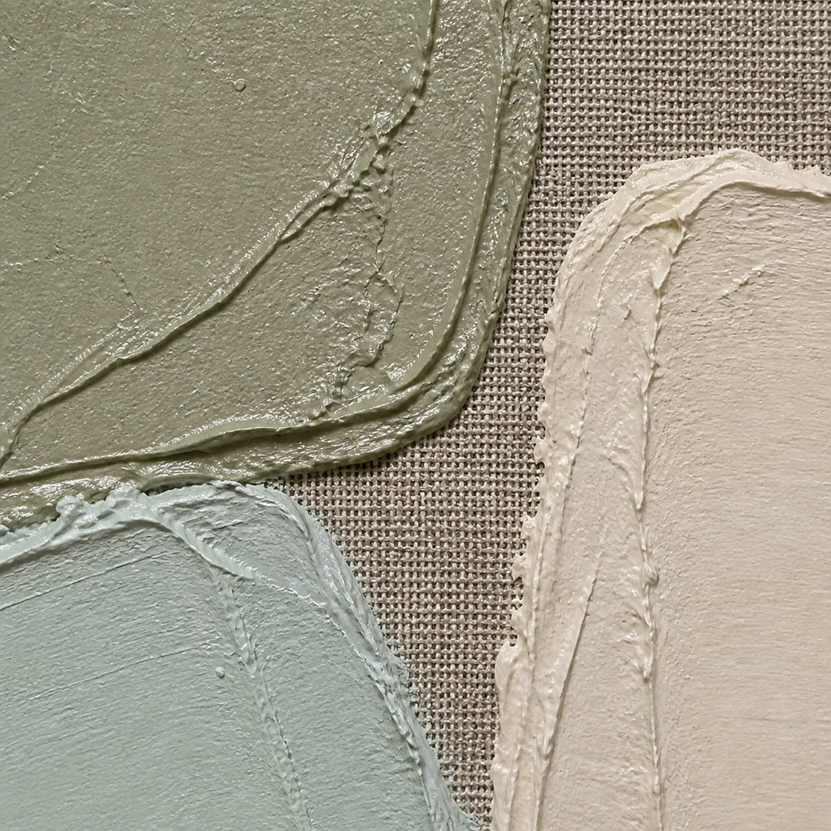 Close-up of thick sage, mint, and ivory paint over woven linen.