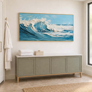 Blue wave artwork above a muted green cabinet holding folded towels beside a window.