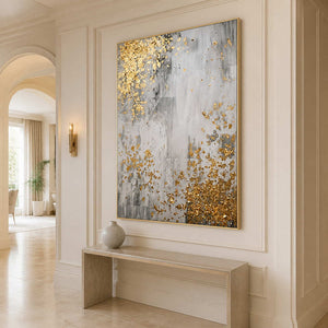 Gold framed gray abstract artwork above a console in a bright arched hallway.