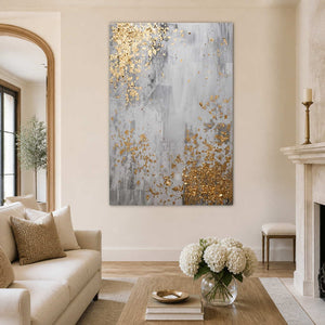 Frameless gray abstract artwork with gold flecks beside a cream living room sofa.