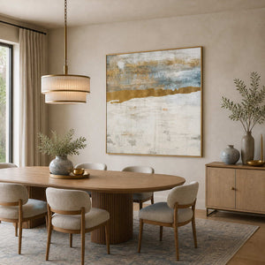 Gold framed blue and cream abstraction beside an oval dining table and upholstered chairs.