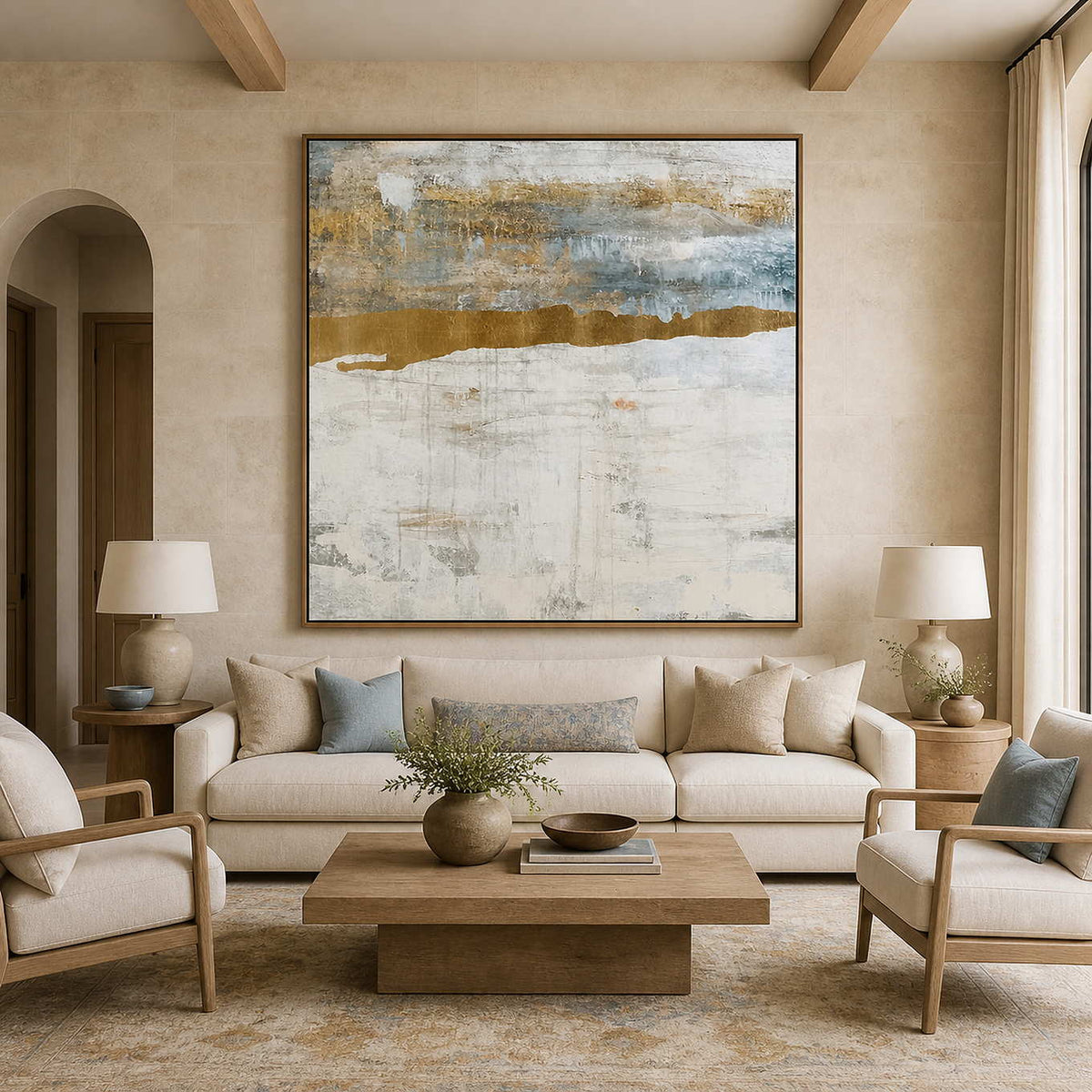 Wood framed pale abstract horizon above a cream sofa with muted blue cushions.