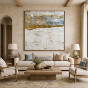 Wood framed pale abstract horizon above a cream sofa with muted blue cushions.
