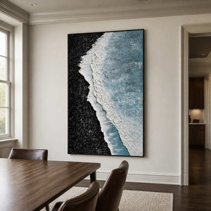 Black framed blue and white coastal abstract beside a wooden dining table.