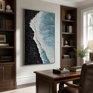 Silver framed coastal texture painting between bookshelves behind a wooden study desk.