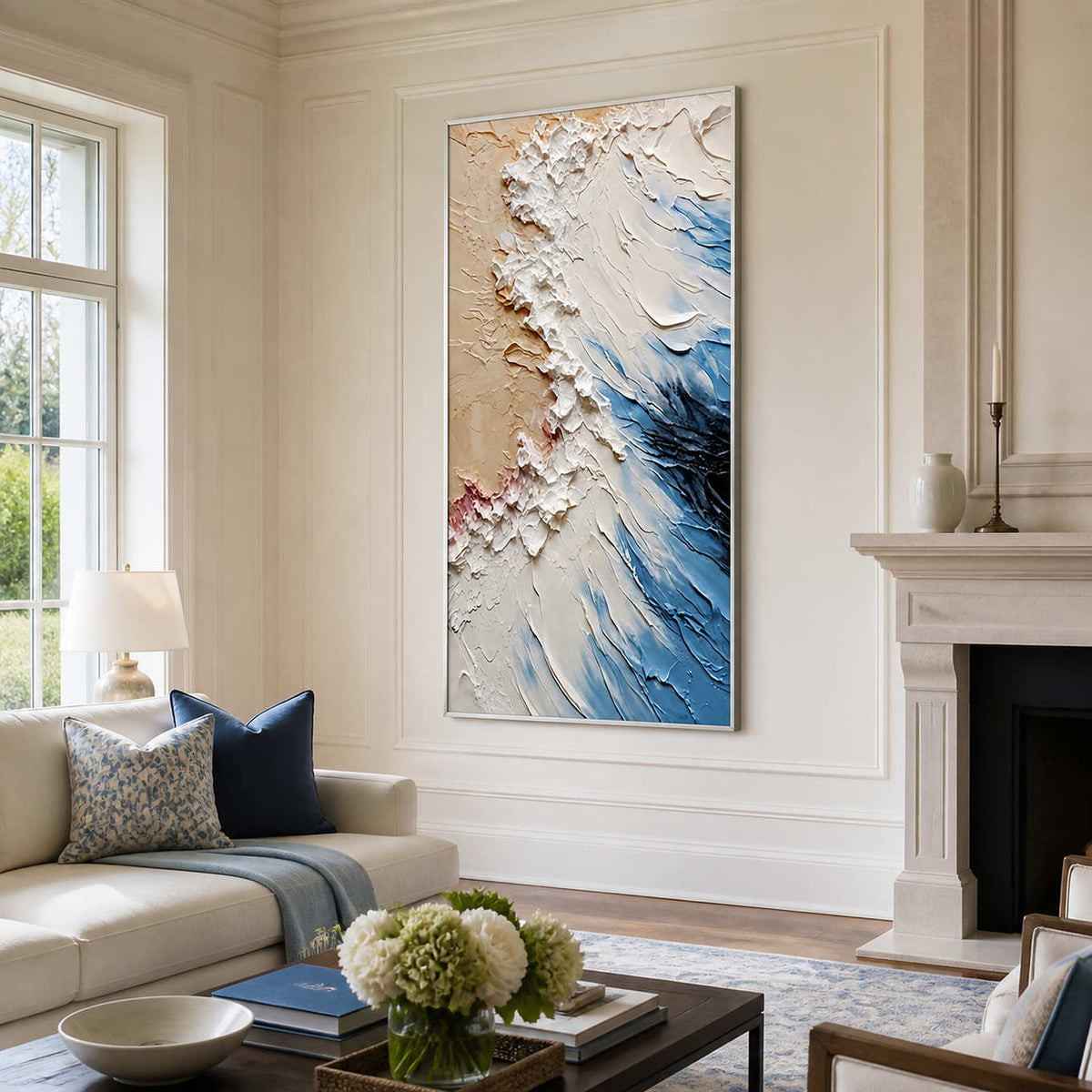 White-framed blue and beige coastal abstract artwork beside a fireplace and cream living room sofa.