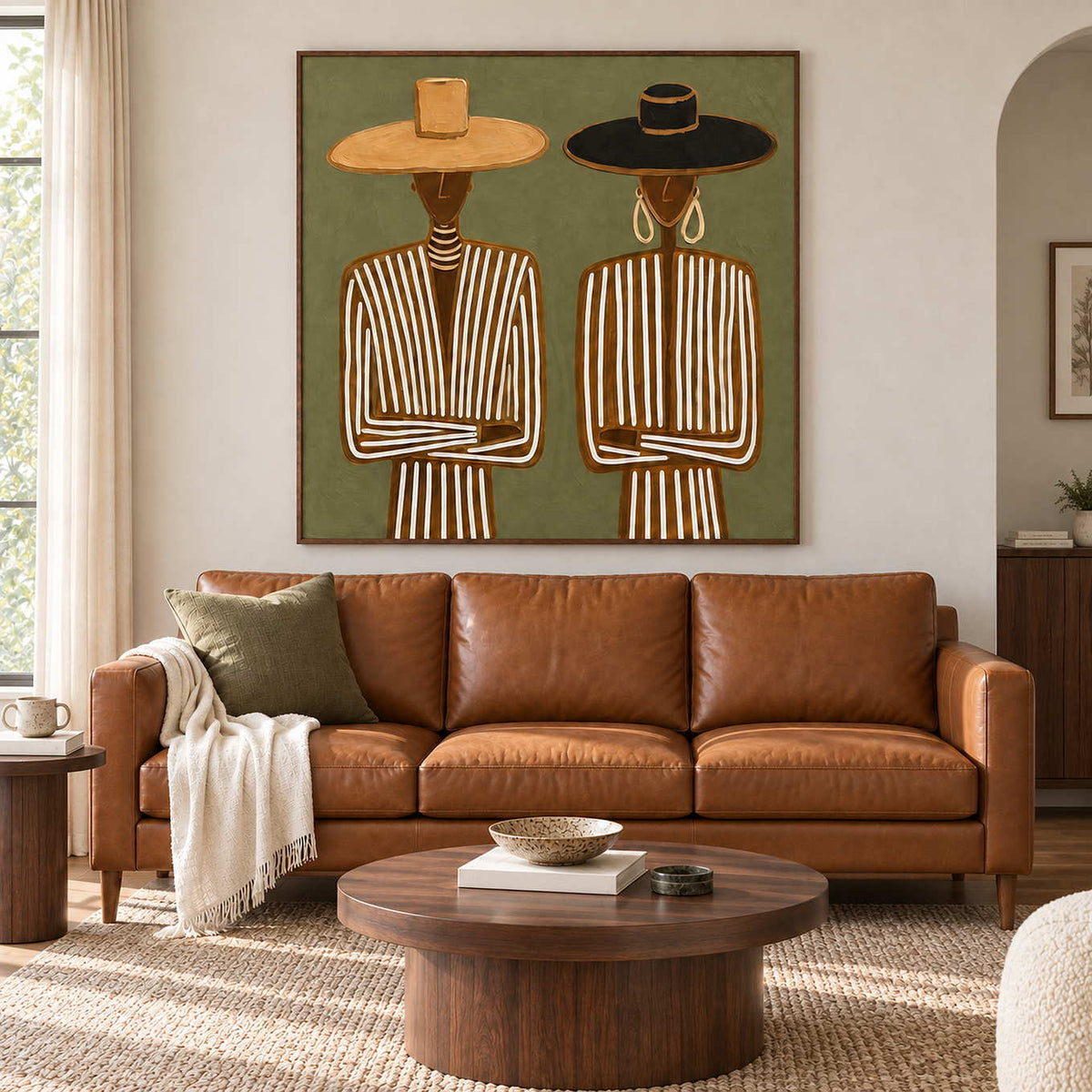 Shared Understanding in a wood frame above a tan leather sofa with olive cushions and a round wood coffee table.