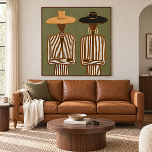 Shared Understanding in a wood frame above a tan leather sofa with olive cushions and a round wood coffee table.