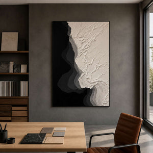 Black framed textured painting beside material samples in an architectural design studio.