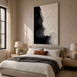 White framed abstract shoreline painting above a softly upholstered bedroom headboard.