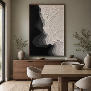 Wood framed black and ivory relief painting beside a wooden dining table.