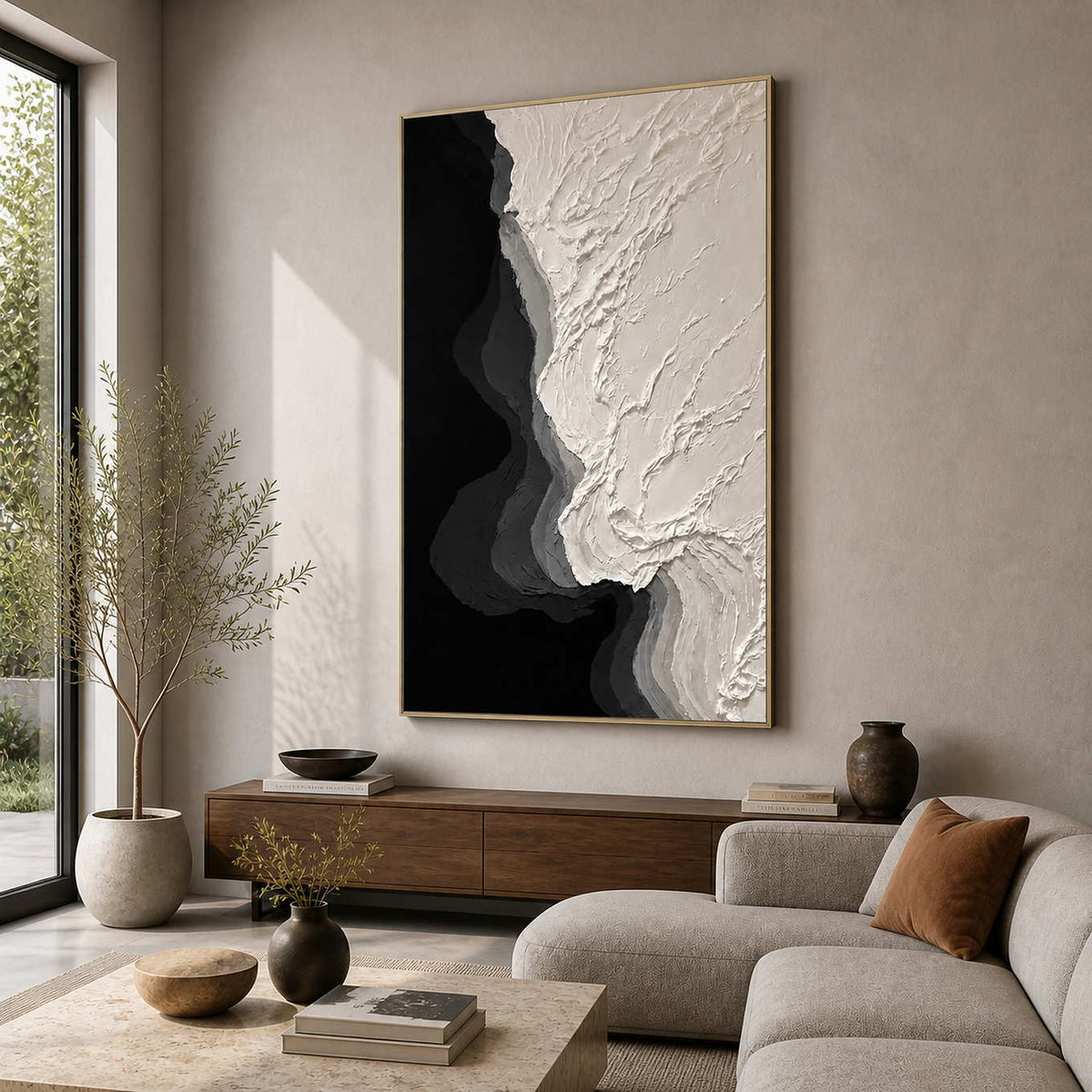 Gold framed ivory and black textured painting beside a living room sofa.