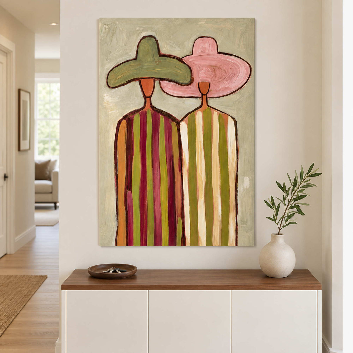 Two-figure painting above a white entry cabinet with a plant.