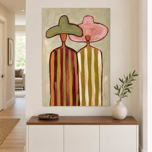 Two-figure painting above a white entry cabinet with a plant.