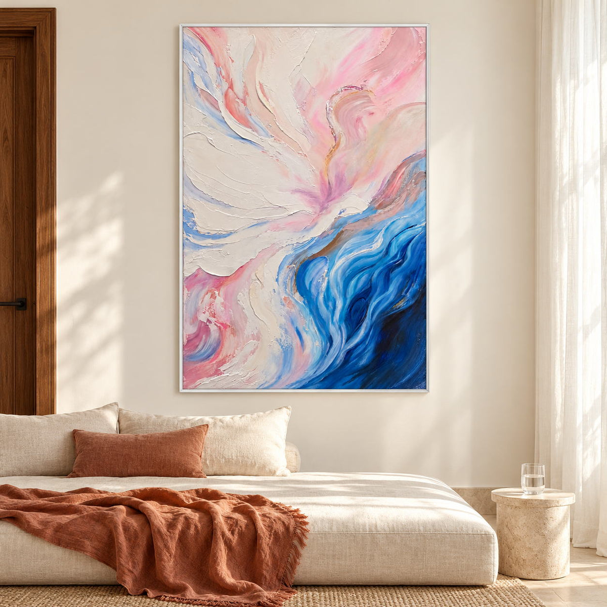 In a bedroom near the bed, an artwork with a white frame shows cream and pink folds flowing into deep blue curves at the lower right.