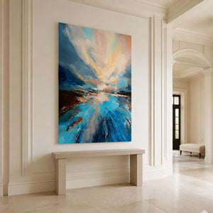 Frameless blue landscape above a pale stone console in a tall cream entryway.