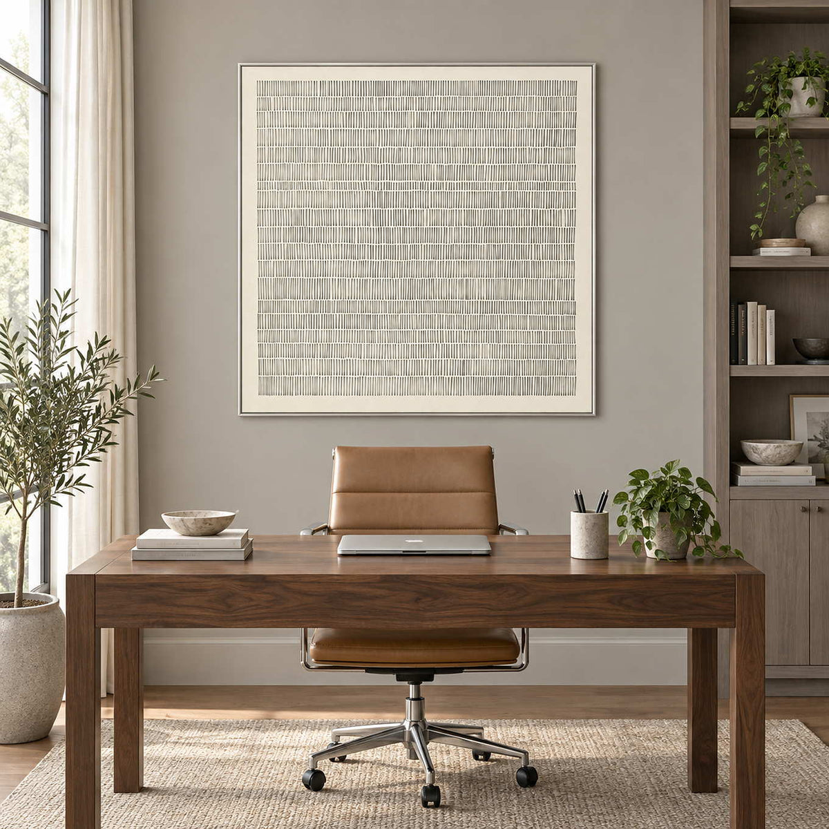Slow and Lasting in a silver frame above a wood desk and tan leather office chair beside shelving and greenery.