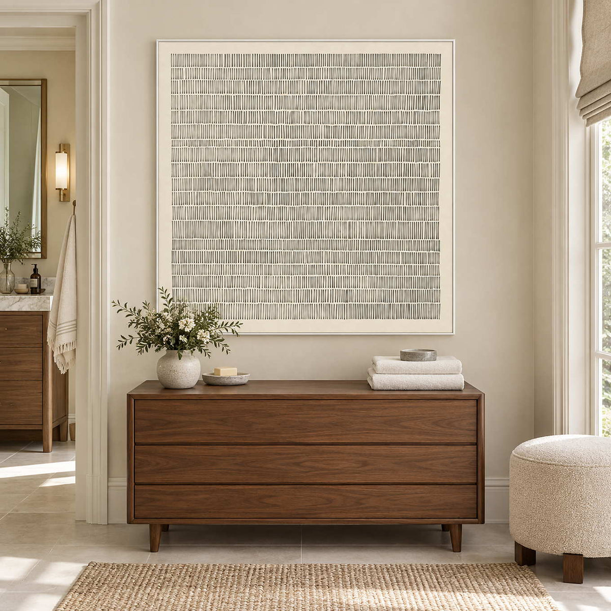 Slow and Lasting in a white frame above a wood cabinet with folded towels and a leafy vase beside a bathroom doorway.