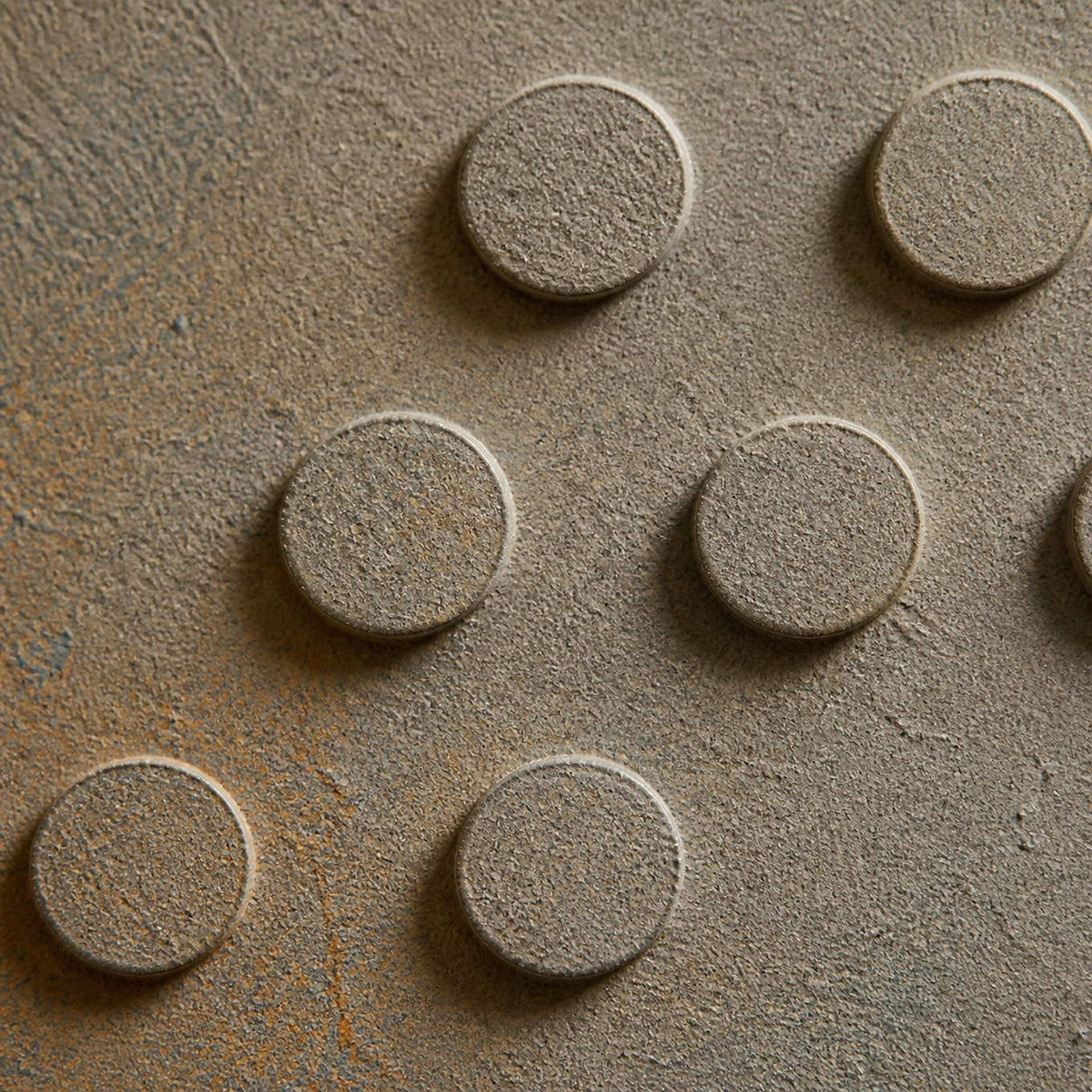 Close-up of raised circular relief and softly weathered blue-gray texture.