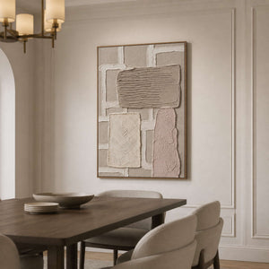 Taupe abstract wall art in a wood frame beside a dining table.